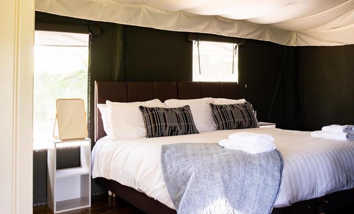 A superking bed made up with white linen and blue blankets and cushions
